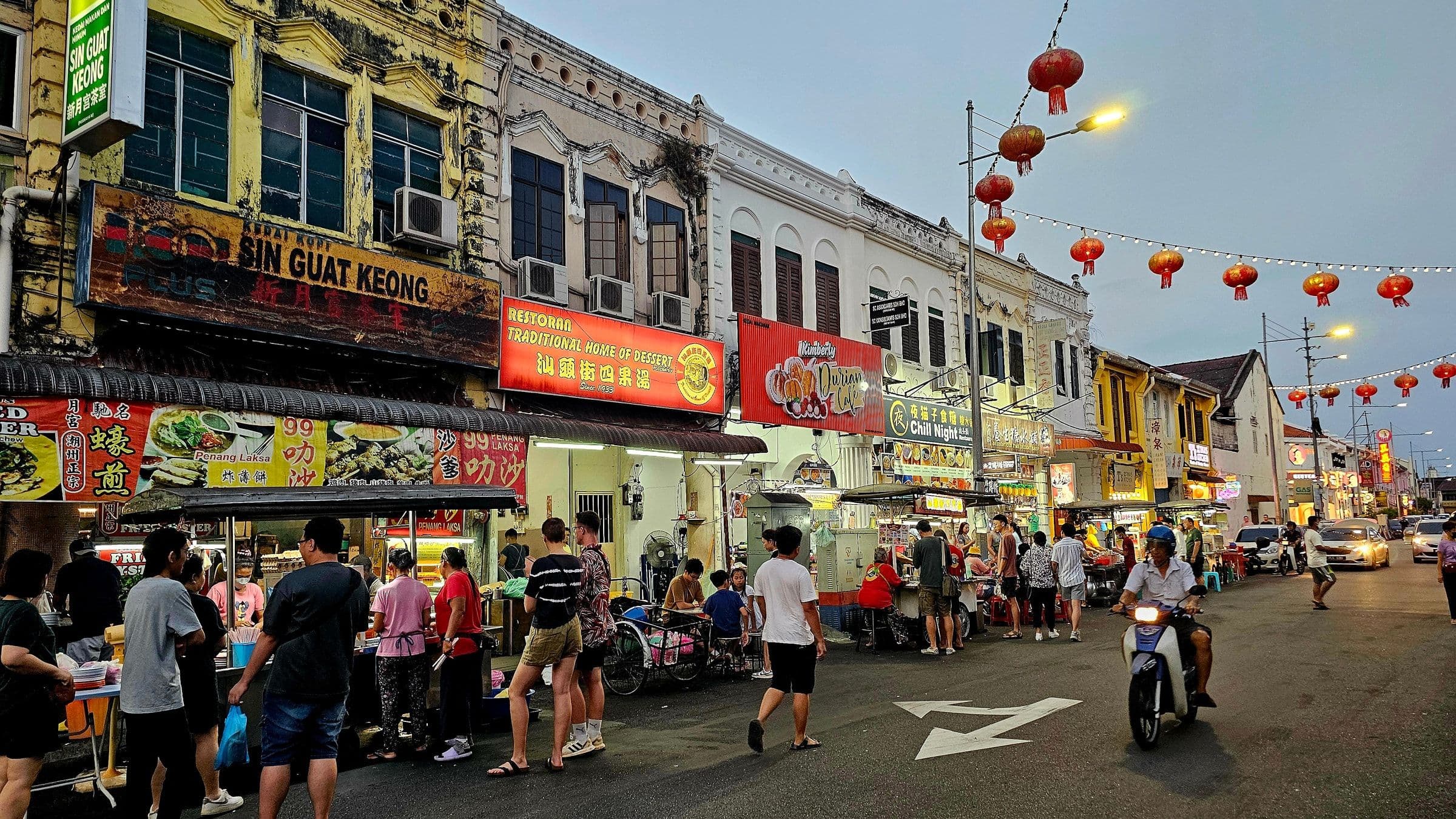 Hawker stalls and shophouse signboards along a George Town street at dusk