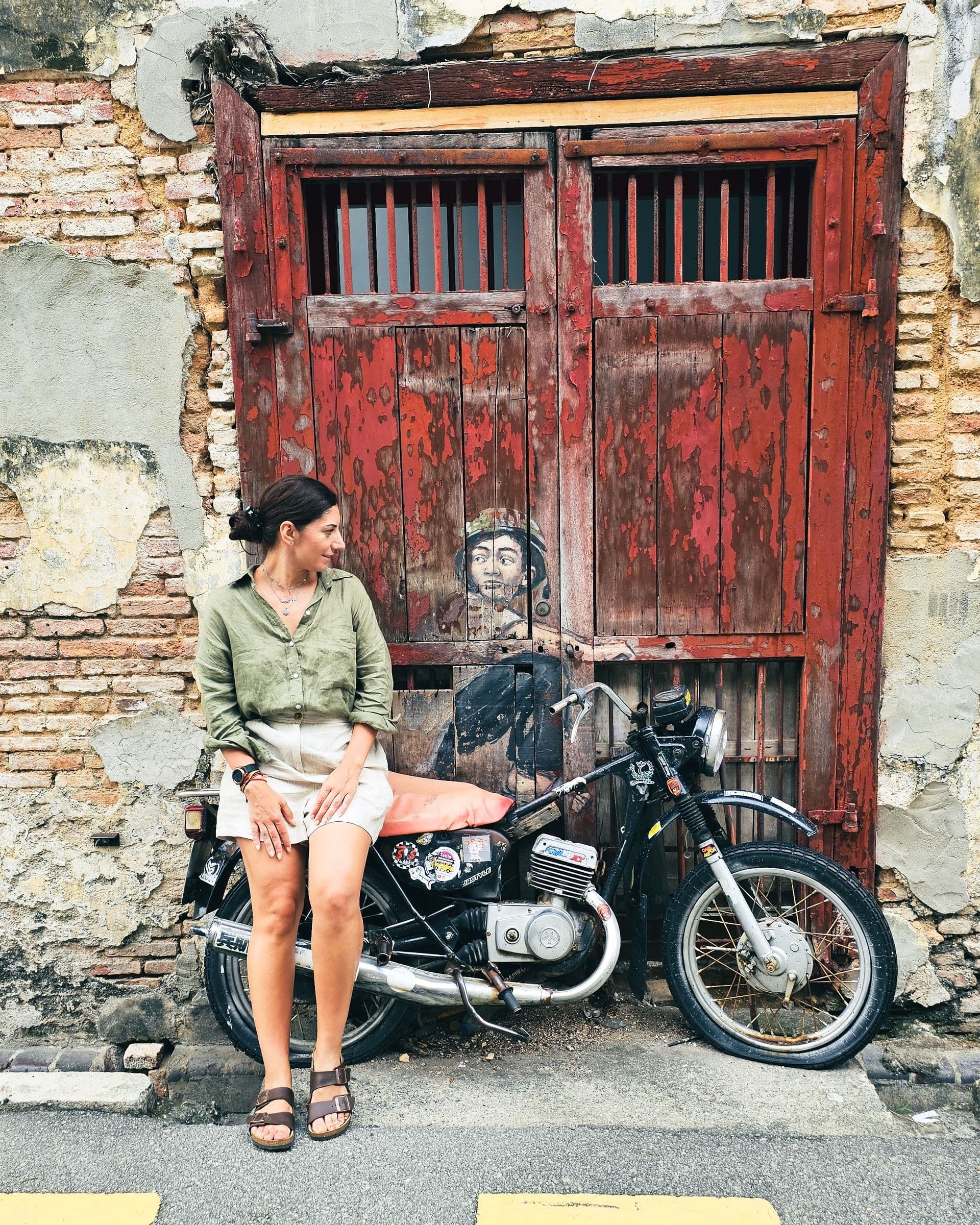 Boy on a Motorbike mural by Ernest Zacharevic, a painted sleeping boy slumped over a real vintage motorcycle on Lebuh Ah Quee